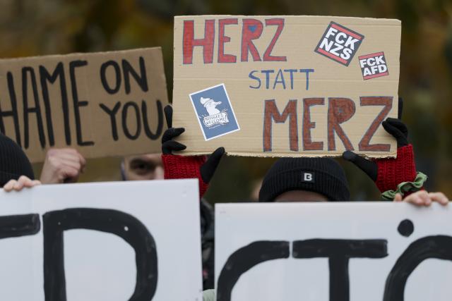 28 October 2025, Saxony, Dresden: A demonstrator holds a placard with the inscription "Herz statt Merz" (Heart instead of Merz) at a demonstration during German Chancellor Friedrich Merz's inaugural visit to the Saxon State Chancellery. Photo: Jan Woitas/dpa