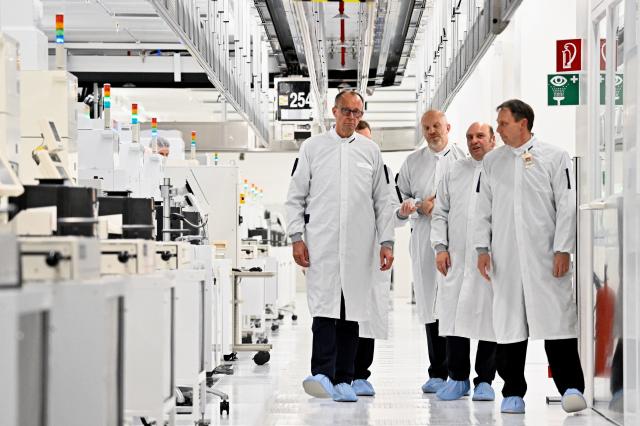 28 October 2025, Saxony, Dresden: German Chancellor Friedrich Merz (L) walks with GlobalFoundries CEO Tim Breen (3rd R) and GlobalFoundries Managing Director Manfred Horstmann (2nd R) during a visit to the test lab in GlobalFoundries' clean room. Photo: Matthias Rietschel/Reuters/Pool/dpa