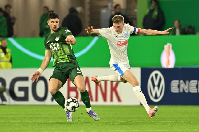 28 October 2025, Lower Saxony, Wolfsburg: VfL Wolfsburg's Konstantinos Koulierakis (L) and Holstein Kiel's Alexander Bernhardsson battle for the ball during the German DFB Cup 2nd round soccer match between VfL Wolfsburg and Holstein Kiel at Volkswagen Arena. Photo: Swen Pförtner/dpa - WICHTIGER HINWEIS: Gemäß den Vorgaben der DFL Deutsche Fußball Liga bzw. des DFB Deutscher Fußball-Bund ist es untersagt, in dem Stadion und/oder vom Spiel angefertigte Fotoaufnahmen in Form von Sequenzbildern und/oder videoähnlichen Fotostrecken zu verwerten bzw. verwerten zu lassen.