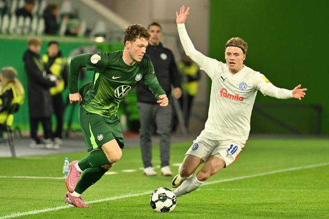28 October 2025, Lower Saxony, Wolfsburg: VfL Wolfsburg's Andreas Skov Olsen (L) and Holstein Kiel's John Tolkin battle for the ball during the German DFB Cup 2nd round soccer match between VfL Wolfsburg and Holstein Kiel at Volkswagen Arena. Photo: Swen Pförtner/dpa - WICHTIGER HINWEIS: Gemäß den Vorgaben der DFL Deutsche Fußball Liga bzw. des DFB Deutscher Fußball-Bund ist es untersagt, in dem Stadion und/oder vom Spiel angefertigte Fotoaufnahmen in Form von Sequenzbildern und/oder videoähnlichen Fotostrecken zu verwerten bzw. verwerten zu lassen.