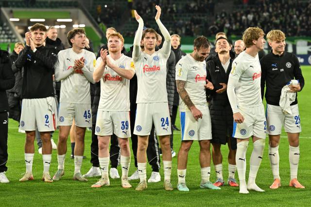 28 October 2025, Lower Saxony, Wolfsburg: Holstein Kiel players celebrate after the German DFB Cup 2nd round soccer match between VfL Wolfsburg and Holstein Kiel at Volkswagen Arena. Photo: Swen Pförtner/dpa - WICHTIGER HINWEIS: Gemäß den Vorgaben der DFL Deutsche Fußball Liga bzw. des DFB Deutscher Fußball-Bund ist es untersagt, in dem Stadion und/oder vom Spiel angefertigte Fotoaufnahmen in Form von Sequenzbildern und/oder videoähnlichen Fotostrecken zu verwerten bzw. verwerten zu lassen.