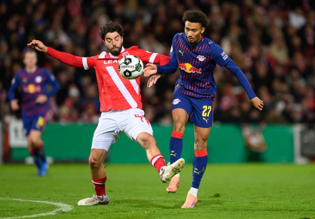 28 October 2025, Brandenburg, Cottbus: Energie Cottbus' Dominik Pelivan (l) and Leipzig's Tidiam Gomis battle for the ball during the German DFB Cup 2nd round soccer match between FC Energie Cottbus and RB Leipzig at Stadion der Freundschaft. Photo: Robert Michael/dpa - WICHTIGER HINWEIS: Gemäß den Vorgaben der DFL Deutsche Fußball Liga bzw. des DFB Deutscher Fußball-Bund ist es untersagt, in dem Stadion und/oder vom Spiel angefertigte Fotoaufnahmen in Form von Sequenzbildern und/oder videoähnlichen Fotostrecken zu verwerten bzw. verwerten zu lassen.