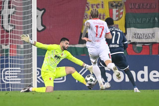28 October 2025, Bavaria, Augsburg: (L-R) Augsburg goalkeeper Nediljko Labrovic, Kristijan Jakie in action against Bochum's Moritz Kwarteng during the German DFB Cup 2nd round soccer match between FC Augsburg and VfL Bochum at WWK-Arena. Photo: Harry Langer/dpa - WICHTIGER HINWEIS: Gemäß den Vorgaben der DFL Deutsche Fußball Liga bzw. des DFB Deutscher Fußball-Bund ist es untersagt, in dem Stadion und/oder vom Spiel angefertigte Fotoaufnahmen in Form von Sequenzbildern und/oder videoähnlichen Fotostrecken zu verwerten bzw. verwerten zu lassen.