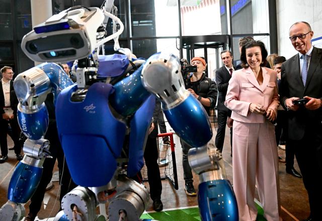 29 October 2025, Berlin: Dorothee Baer (2nd R), German Minister for Research, Technology and Aerospace, looks on as Chancellor Friedrich Merz (R) steers DLR's humanoid walking robot TORO (TOrque-controlled humanoid RObot), at the presentation of the so-called "Hightech Agenda Germany - Debate, Conference, Networking" on the EUREF-Campus. Photo: Tobias Schwarz/POOL AFP/dpa