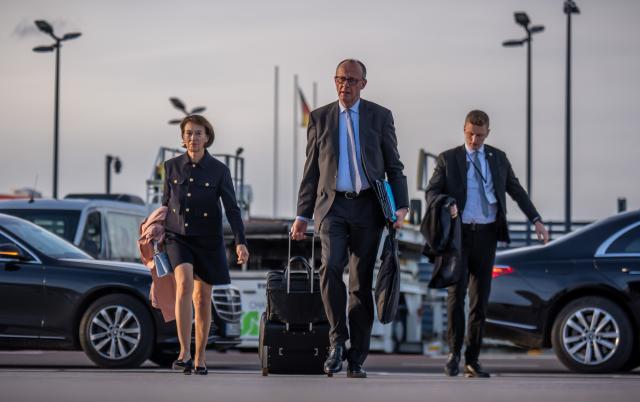 29 October 2025, Brandenburg, Schoenefeld: German Chancellor Friedrich Merz (C) walks alongside his wife Charlotte to an air force plane to fly to Turkey. Photo: Michael Kappeler/dpa