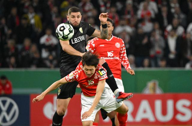 29 October 2025, Rhineland-Palatinate, Mainz: FSV Mainz's Jae-sung Lee and Stuttgart's Jeff Chabot battle for the ball during the German DFB Cup 2nd round soccer match between FSV Mainz 05 and VfB Stuttgart at Mewa Arena. Photo: Torsten Silz/dpa - WICHTIGER HINWEIS: Gemäß den Vorgaben der DFL Deutsche Fußball Liga bzw. des DFB Deutscher Fußball-Bund ist es untersagt, in dem Stadion und/oder vom Spiel angefertigte Fotoaufnahmen in Form von Sequenzbildern und/oder videoähnlichen Fotostrecken zu verwerten bzw. verwerten zu lassen.