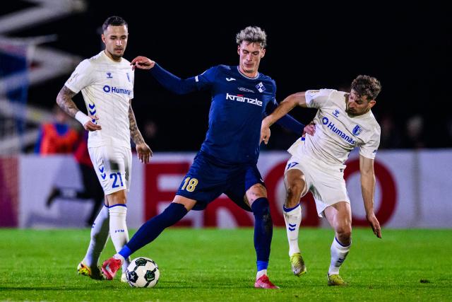 29 October 2025, Bavaria, Illertissen: Illertissen's Luis Pfaumann (C) and Magdeburg's Falko Michel (L) and Alexander Nollenberger battle for the ball during the German DFB Cup 2nd round soccer match between FV Illertissen and 1. FC Magdeburg at Voehlin Stadium. Photo: Tom Weller/dpa - WICHTIGER HINWEIS: Gemäß den Vorgaben der DFL Deutsche Fußball Liga bzw. des DFB Deutscher Fußball-Bund ist es untersagt, in dem Stadion und/oder vom Spiel angefertigte Fotoaufnahmen in Form von Sequenzbildern und/oder videoähnlichen Fotostrecken zu verwerten bzw. verwerten zu lassen.