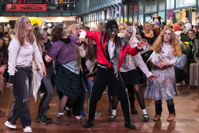 31 October 2025, Hamburg: Michael Jackson impersonator Koffi Missah dances the iconic Thriller choreography with around 150 fans from Germany, Austria and Switzerland dressed as zombies in the Wandelhalle at the main station. Photo: Marcus Golejewski/dpa