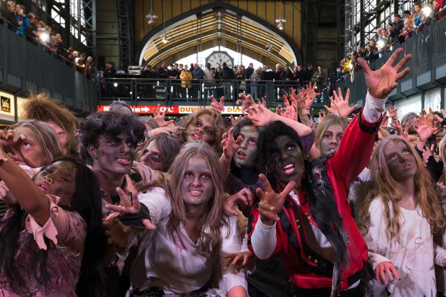 31 October 2025, Hamburg: Michael Jackson impersonator Koffi Missah dances the iconic Thriller choreography with around 150 fans from Germany, Austria and Switzerland dressed as zombies in the Wandelhalle at the main station. Photo: Marcus Golejewski/dpa