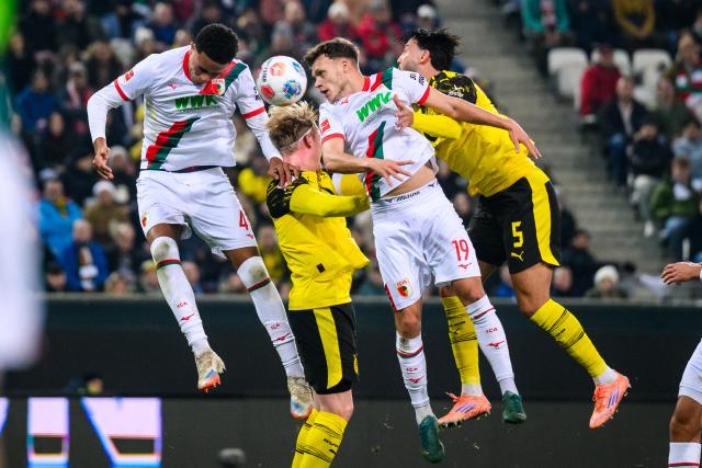 31 October 2025, Bavaria, Augsburg: Augsburg's Noahkai Banks (L) and Robin Fellhauer (2nd R) battle for the ball with Borussia Dortmund's Julian Brandt (2nd L) and Ramy Bensebaini during the German Bundesliga soccer match between FC Augsburg and Borussia Dortmund at WWK-Arena. Photo: Tom Weller/dpa - WICHTIGER HINWEIS: Gemäß den Vorgaben der DFL Deutsche Fußball Liga bzw. des DFB Deutscher Fußball-Bund ist es untersagt, in dem Stadion und/oder vom Spiel angefertigte Fotoaufnahmen in Form von Sequenzbildern und/oder videoähnlichen Fotostrecken zu verwerten bzw. verwerten zu lassen.