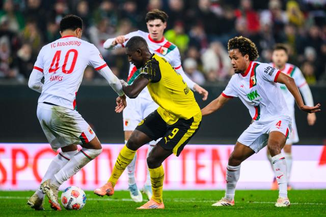 31 October 2025, Bavaria, Augsburg: Borussia Dortmund's Serhou Guirassy (C) battles for the ball with Augsburg's Noahkai Banks (L) and Han-Noah Massengo during the German Bundesliga soccer match between FC Augsburg and Borussia Dortmund at WWK-Arena. Photo: Tom Weller/dpa - WICHTIGER HINWEIS: Gemäß den Vorgaben der DFL Deutsche Fußball Liga bzw. des DFB Deutscher Fußball-Bund ist es untersagt, in dem Stadion und/oder vom Spiel angefertigte Fotoaufnahmen in Form von Sequenzbildern und/oder videoähnlichen Fotostrecken zu verwerten bzw. verwerten zu lassen.