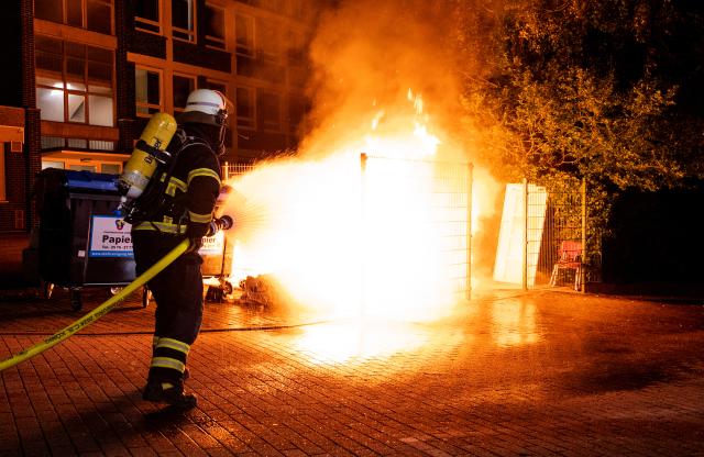 31 October 2025, Hamburg: Firefighters extinguish burning garbage containers in the Harburg district during the Halloween celebrations. Photo: Daniel Bockwoldt/dpa