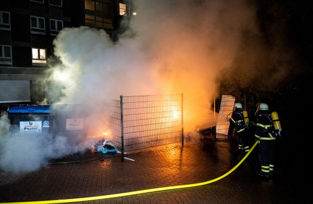 31 October 2025, Hamburg: Firefighters extinguish burning garbage containers in the Harburg district during the Halloween celebrations. Photo: Daniel Bockwoldt/dpa