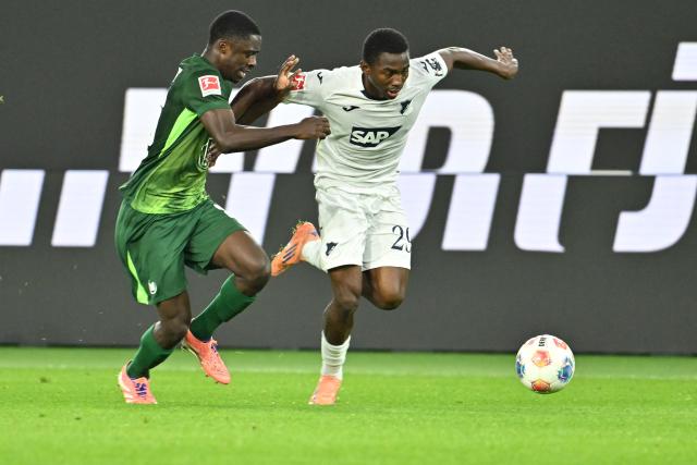 02 November 2025, Lower Saxony, Wolfsburg: Hoffenheim's Bazoumana Toure in action against Wolfsburg's Sael Kumbedi during the German Bundesliga soccer match between VfL Wolfsburg and TSG Hoffenheim at the Volkswagen Arena. Photo: Swen Pförtner/dpa - IMPORTANT NOTICE: DFL and DFB regulations prohibit any use of photographs as image sequences and/or quasi-video.