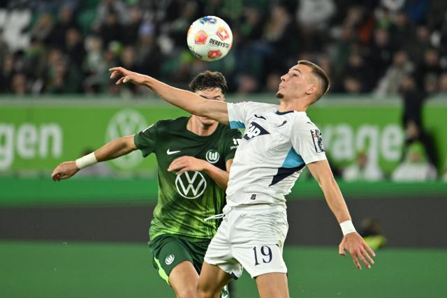 02 November 2025, Lower Saxony, Wolfsburg: Hoffenheim's Tim Lemperle (R) in action against Wolfsburg's Jenson Seelt during the German Bundesliga soccer match between VfL Wolfsburg and TSG Hoffenheim at the Volkswagen Arena. Photo: Swen Pförtner/dpa - IMPORTANT NOTICE: DFL and DFB regulations prohibit any use of photographs as image sequences and/or quasi-video.