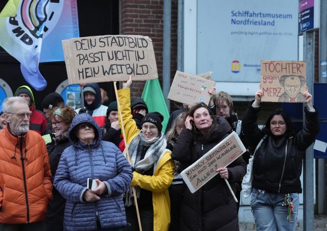 03 November 2025, Schleswig-Holstein, Husum: Protesters hold placards and banners in front of the town hall during the inaugural visit of Chancellor Merz, who is on his first official trip to Schleswig-Holstein. Photo: Marcus Brandt/dpa