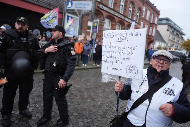 03 November 2025, Schleswig-Holstein, Husum: Protesters hold placards and banners in front of the town hall during the inaugural visit of Chancellor Merz, who is on his first official trip to Schleswig-Holstein. Photo: Marcus Brandt/dpa