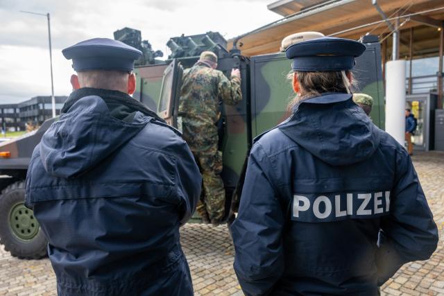 FILED - 28 October 2025, Bavaria, Essenbach: Police forces stand in front of a Bundeswehr vehicle during the media day of the large-scale Marshal Power exercise. German prosecutors have launched investigations into three suspects after a shot was fired at a soldier during a large-scale military exercise in Bavaria, a spokeswoman said on Monday. Photo: Armin Weigel/dpa