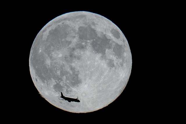 05 November 2025, Berlin: An airplane flies past the full moon over Berlin. Photo: Kay Nietfeld/dpa