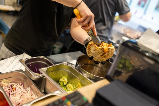 PRODUCTION - 07 November 2025, Baden-Württemberg, Karlsruhe: An employee prepares an Octopus Doener sandwich at the "Pescobar" restaurant in Karlsruhe. Photo: Philipp von Ditfurth/dpa