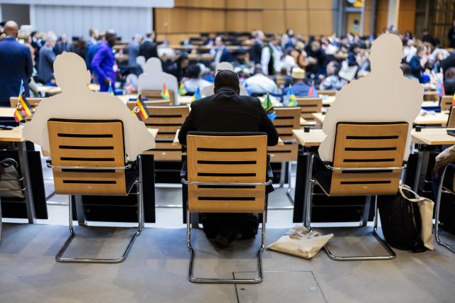 08 November 2025, Berlin: A participant sits next to cardboard displays showing absent delegates during the opening session of the World Liberty Congress at the Berlin House of Representatives, marking the start of Berlin Freedom Week. Photo: Christoph Soeder/dpa