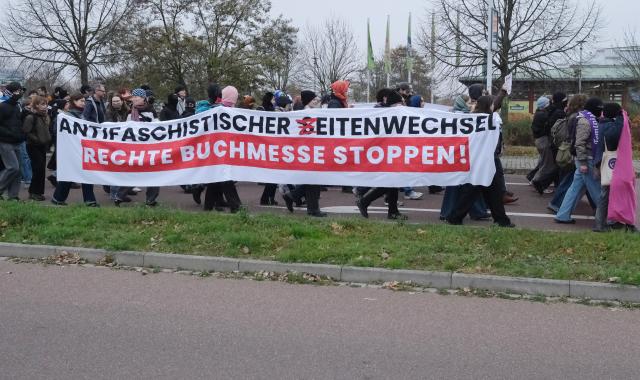 08 November 2025, Saxony-Anhalt, Halle: Left-wing activists hold banners in front of a police cordon at the "Seitenwechsel" book fair, where conservative and right-wing publishers are meeting on November 8-9, 2025. Photo: Sebastian Willnow/dpa