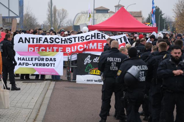 08 November 2025, Saxony-Anhalt, Halle: Left-wing activists hold banners in front of a police cordon during the "Seitenwechsel" book fair, where conservative and right-wing publishers are holding an industry meeting on November 8 and 9. Photo: Sebastian Willnow/dpa
