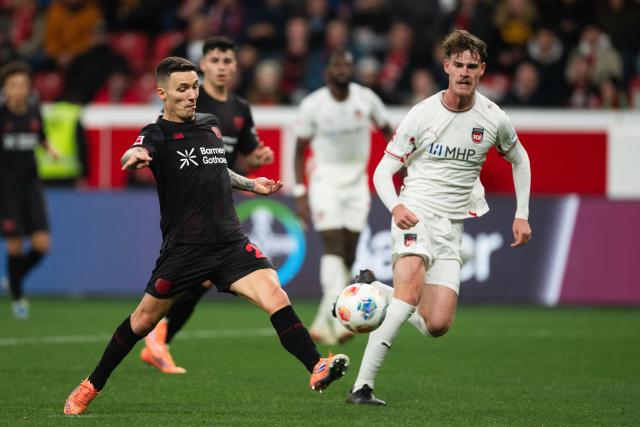 08 November 2025, North Rhine-Westphalia, Leverkusen: Bayer Leverkusen's Alex Grimaldo (L) plays the ball during the German Bundesliga soccer match between Bayer 04 Leverkusen and 1. FC Heidenheim at BayArena. Photo: Marius Becker/dpa - IMPORTANT NOTICE: DFL and DFB regulations prohibit any use of photographs as image sequences and/or quasi-video.