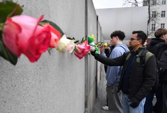 09 November 2025, Berlin: People place flowers to mark the 36th anniversary of the Berlin wall fall,  at the Wall memorial on Bernauer Strasse. Photo: Paul Zinken/dpa