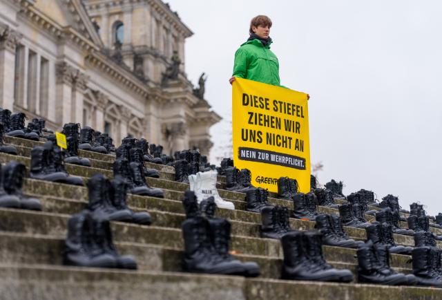 10 November 2025, Berlin: Greenpeace activists have placed military boots with the inscription "No to compulsory military service" in front of the Bundestag. An expert hearing of the Bundestag's Defense Committee on the Military Service Act is to discuss compulsory military service. Photo: Michael Kappeler/dpa