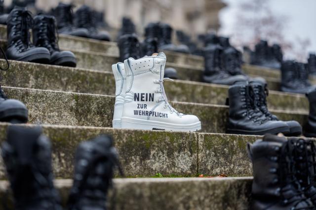 10 November 2025, Berlin: Greenpeace activists have placed military boots with the inscription "No to compulsory military service" in front of the Bundestag. An expert hearing of the Bundestag's Defense Committee on the Military Service Act is to discuss compulsory military service. Photo: Michael Kappeler/dpa