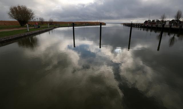 10 November 2025, Mecklenburg-Western Pomerania, Ahrenshoop: Dark clouds are reflected in the Bodden harbor of the Baltic seaside resort. Calm autumn weather with lots of dark clouds and sunny spells dominates the north. Photo: Bernd Wüstneck/dpa
