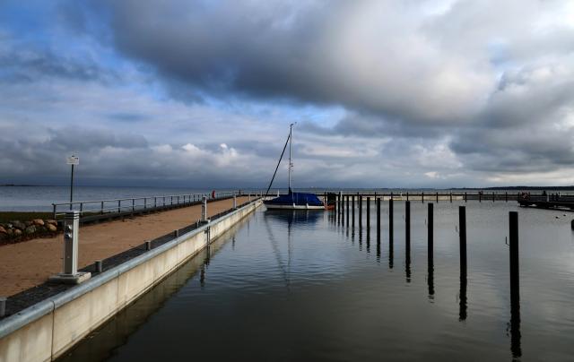 10 November 2025, Mecklenburg-Western Pomerania, Ahrenshoop: A lonely sailing boat winters in the Bodden harbor of the Baltic Sea resort. Calm autumn weather with lots of dark clouds and sunny spells dominates the north. Photo: Bernd Wüstneck/dpa
