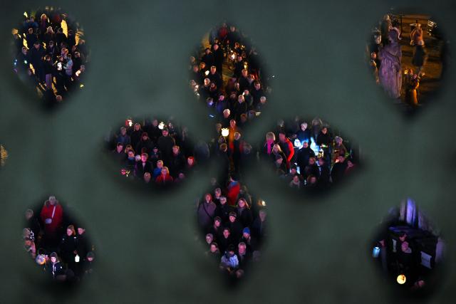 10 November 2025, Thuringia, Erfurt: eople gather on Cathedral Square for St. Martin's Day, photographed through a building ornament. The cumenical celebration on November 10 commemorates Martin Luther and St. Martin as the city's patron saint. Photo: Martin Schutt/dpa