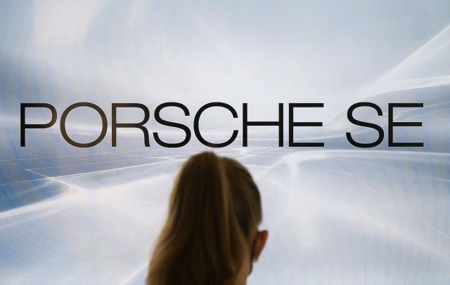 FILED - 29 March 2022, Baden-Württemberg, Stuttgart: A woman stands in front of a monitor with the Porsche SE logo. Photo: Marijan Murat/dpa