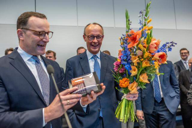 11 November 2025, Berlin: German Chancellor Friedrich Merz holds flowers he received for his 70th birthday next to Jens Spahn (L), Christian Democratic Union (CDU)/Chrisitan Social Union (CSU) parliamentary group leader, at the start of the parliamentary group meeting at the German Bundestag. Photo: Michael Kappeler/dpa