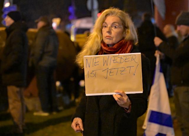 11 November 2025, Bavaria, Munich: A demonstrator holds a sign reading "Never again is now" at the rally of the "Munich is colorful" alliance against anti-Semitism, following recent protests and actions against performances by the Israel Philharmonic Orchestra with its music director Lahav Shani against the backdrop of the Gaza war. Photo: Malin Wunderlich/dpa