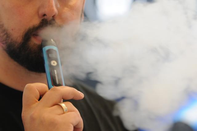 FILED - 19 September 2024, North Rhine-Westphalia, Dortmund: The Managing Director of the German subsidiary of e-cigarette manufacturer Reymont, Selim Oezder, stands at his company's stand at the Intertabac trade fair and uses a vape, as the devices are also known. Vapes are "compromising children's human rights," academics have said as they called for more regulation of e-cigarettes to protect young people. Photo: Wolf von Dewitz/dpa