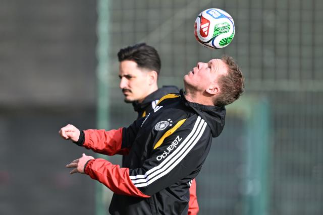 13 November 2025, Lower Saxony, Wolfsburg: Germany coach Julian Nagelsmann (F) heads the ball in front of assistant coach Benjamin Huebner during a training session ahead of Friday's FIFA World Cup qualifier soccer match against Luxembourg. Photo: David Inderlied/dpa