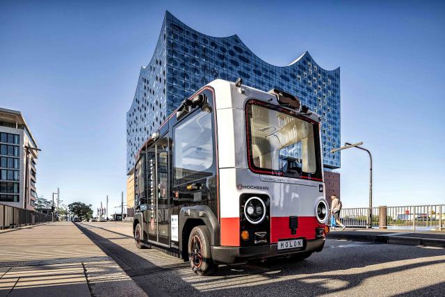 HANDOUT - 13 November 2025, Hamburg: A photo provided by Holon shows the "HOLON urban", a new autonomous electric shuttle, in front of the Elbphilharmonie concert hall. Following approval by the German Federal Motor Transport Authority (KBA), Holon is allowed to test the shuttle in autonomous driving mode with a safety driver throughout Germany. Photo: -/Holon/dpa - ACHTUNG: Nur zur redaktionellen Verwendung im Zusammenhang mit der aktuellen Berichterstattung und nur mit vollständiger Nennung des vorstehenden Credits