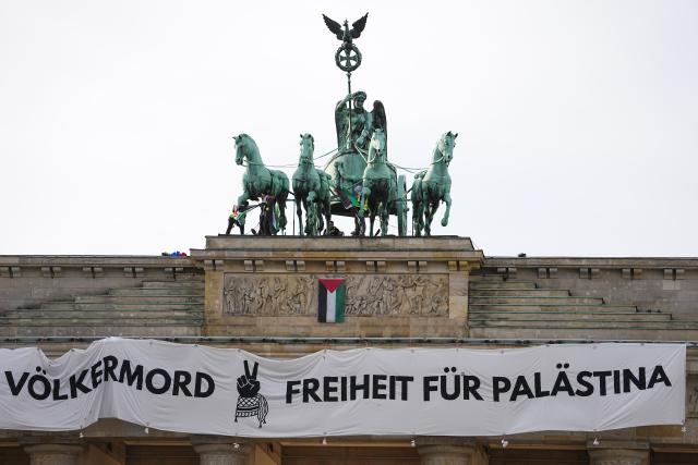 13 November 2025, Berlin: Pro-Palestine activists hang a banner climbed onto the Brandenburg Gate in Berlin. Photo: Kay Nietfeld/dpa