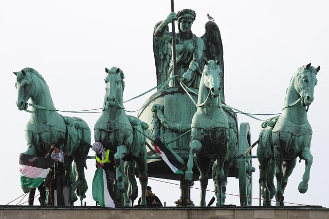 13 November 2025, Berlin: Pro-Palestine activists climb onto the Brandenburg Gate in Berlin holding Palestinian flags. Photo: Kay Nietfeld/dpa