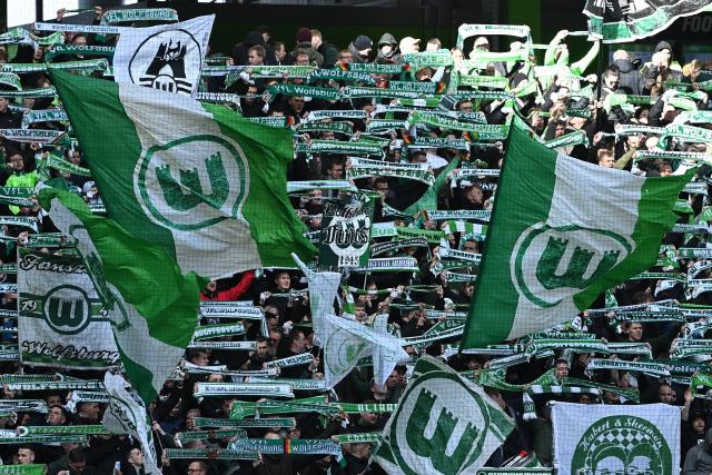 FILED - 16 March 2024, Lower Saxony, Wolfsburg: Wolfsburg fans wave their flags during the German Bundesliga soccer match between VfL Wolfsburg and FC Augsburg at the Volkswagen Arena. Photo: Swen Pförtner/dpa - IMPORTANT NOTE: In accordance with the regulations of the DFL German Football League and the DFB German Football Association, it is prohibited to utilize or have utilized photographs taken in the stadium and/or of the match in the form of sequential images and/or video-like photo series.