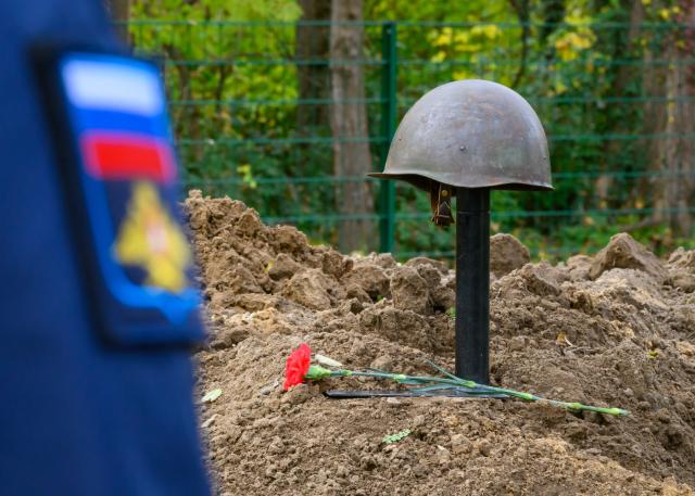 14 November 2025, Brandenburg, Lebus: A Russian soldier stands at the Soviet war cemetery in front of a steel helmet of a Soviet soldier who died in the Second World War. The German War Graves Commission in Brandenburg is fulfilling its humanitarian mission with the silent burial of 39 Soviet soldiers, which recovered from various locations in Brandenburg in recent years. Photo: Patrick Pleul/dpa