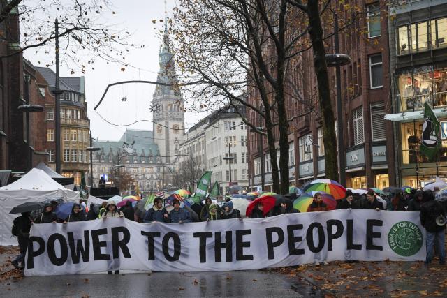 14 November 2025, Hamburg: Supporters of the climate movement Fridays for Future (FFF) hold a banner with the slogan "Power to the People" during a demonstration on Moenckebergstrasse in Hamburg city center. Photo: Christian Charisius/dpa