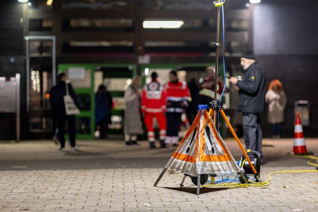 15 November 2025, Bavaria, Nuremberg: Citizens and rescue workers stand in front of a care center that was set up as part of an evacuation due to an unexploded bomb. A large-scale evacuation has begun ahead of the planned defusing of an aerial bomb in Nuremberg. Up to 21,000 citizens had to leave their homes within a radius of 800 meters. It was the largest evacuation operation ever required in Nuremberg following the discovery of a world war bomb. Photo: Daniel Karmann/dpa