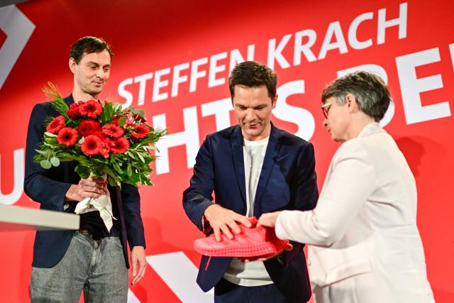 15 November 2025, Berlin: Martin Hikel (L), Chairman of the SPD Berlin and District Mayor of Neukölln, and Nicola Boecker-Giannini (SPD), Chairwoman of the SPD Berlin, present Steffen Krach, the SPD's lead candidate for the 2026 election to the Berlin House of Representatives, with red running shoes after his nomination during the SPD Berlin state party conference. The top candidate for the election to the Berlin House of Representatives on September 20, 2026 is to be chosen at the party conference. Photo: Sebastian Christoph Gollnow/dpa