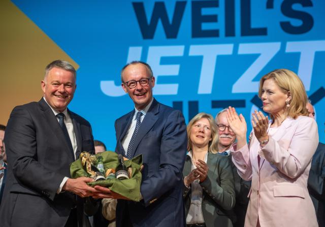 15 November 2025, Rhineland-Palatinate, Morbach: Rhineland-Palatinate Christian Democratic Union of Germany (CDU) party chairman Patrick Schnieder (L) presents German Chancellor Friedrich Merz with a wine gift at the Rhineland-Palatinate CDU state party conference in the presence of Bundestag President Julia Kloeckner. Among other things, the delegates elected the list of candidates for the 2026 state elections. Photo: Harald Tittel/dpa