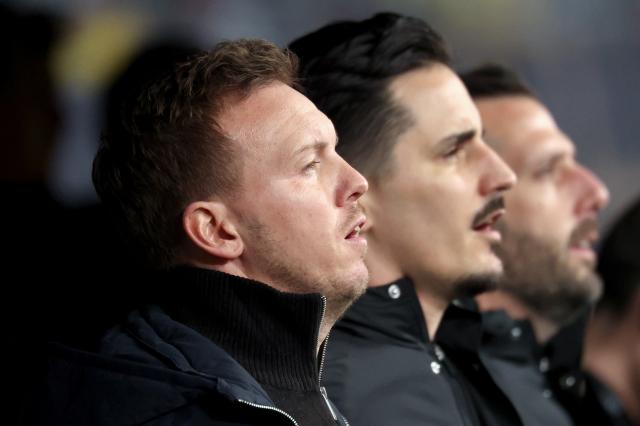 17 November 2025, Saxony, Leipzig: (L-R) Germany coach Julian Nagelsmann, assistant coach Benjamin Huebner and assistant coach, Mads Buttgereit, singing the anthem ahead of the FIFA World Cup European qualifying soccer match between Germany and Slovakia at Red Bull Arena. Photo: Christian Charisius/dpa