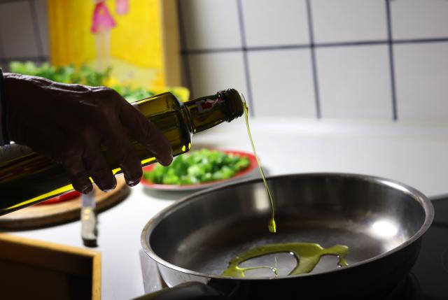 FILED - 02 August 2025, Bavaria, Kaufbeuren: ILLUSTRATION - A woman pours olive oil into a pan while cooking. Photo: Karl-Josef Hildenbrand/dpa